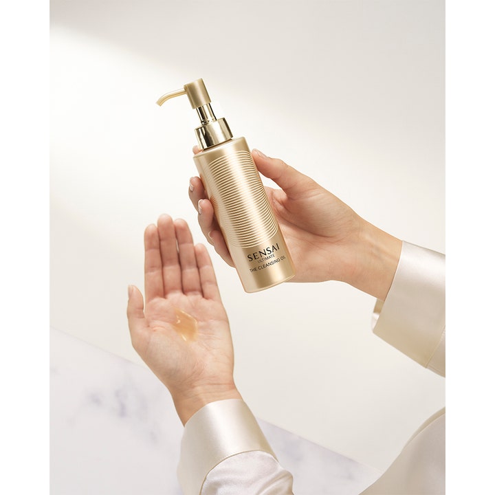 Sensai Ultimate The Cleansing Oil 150 ml ansiktsrens i gullflaske som helles i en håndflate