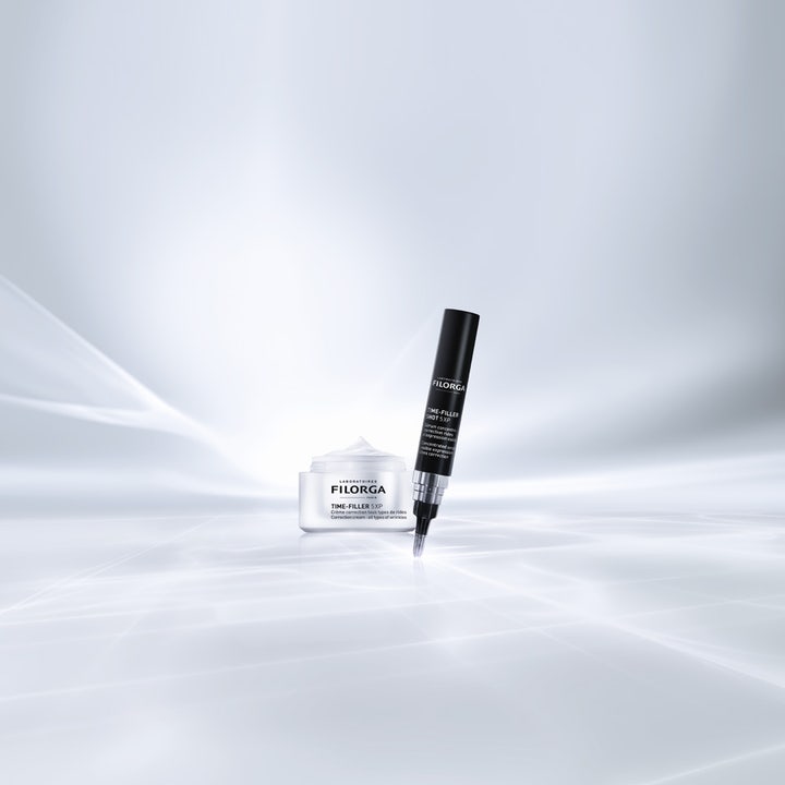 FILORGA Time-Filler Shot 5XP 15 ml serum i svart presisjonspenn ved siden av hvit krukke med ansiktskrem mot rynker.