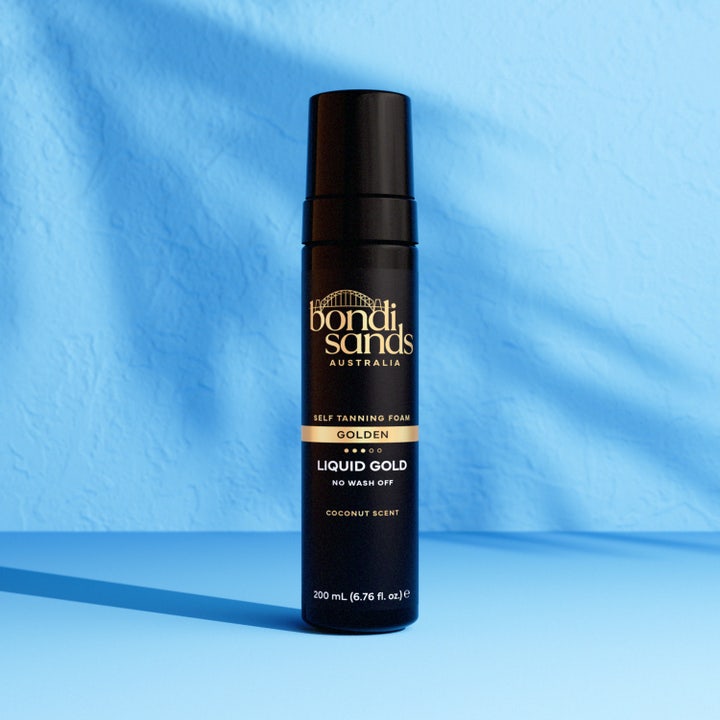 Bondi Sands Liquid Gold Self Tanning Foam 200 ml selvbruning i sort flaske mot blå bakgrunn som gir glød