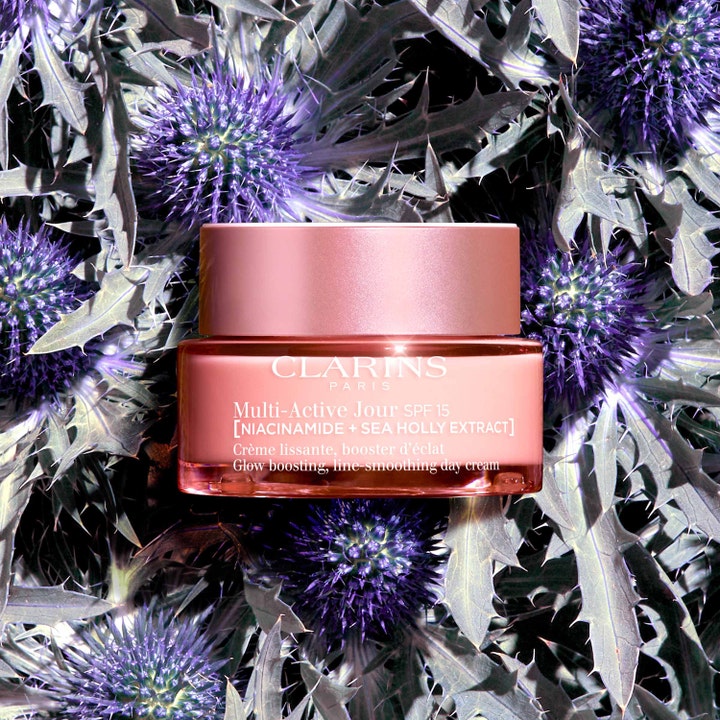 Clarins Multi-Active Jour SPF 15 50 ml glødgivende dagkrem med niacinamide i rosa krukke lagt på lilla strandtorn.