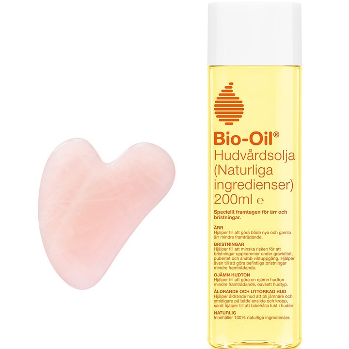 Bio-Oil Hudpleieolje 200 ml mot arr og strekkmerker vist med gul olje og en hjerteformet rosa gua sha-stein.