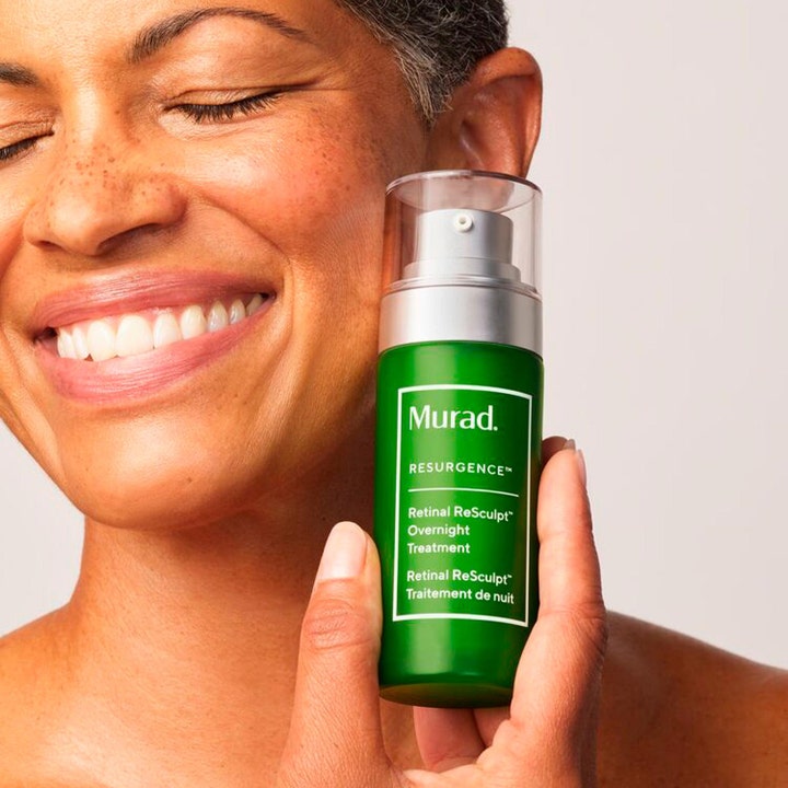 Murad Retinal ReSculpt Treatment 30 ml oppstrammende nattserum i grønn flaske holdt av en smilende kvinne.