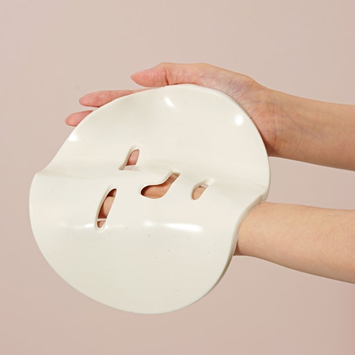 Dr. Ceuracle Expert Collagen Firming Modeling Mask 30 g oppstrammende ansiktsmaske med tykk og hvit gummitekstur holdt i hendene.