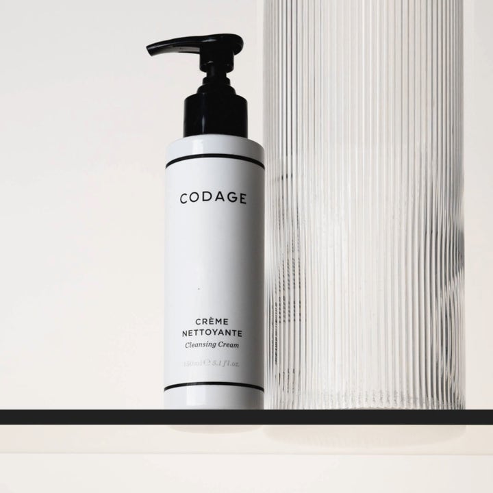 Codage Paris The Cleansing Cream 150 ml rensende ansiktskrem i hvit pumpeflaske ved siden av en riflet glassvase