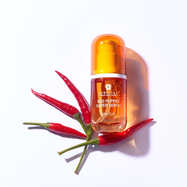 Erborian Red Pepper Super Serum 30 ml glødgivende ansiktsserum i oransje flaske omgitt av ferske røde chilipepper