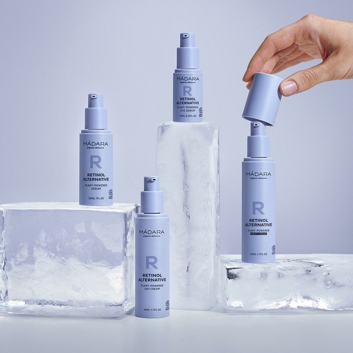 MÁDARA Retinol Alternative Eye Serum 15 ml pleiende øyeserum i lilla flasker på isblokker der en hånd åpner lokket.