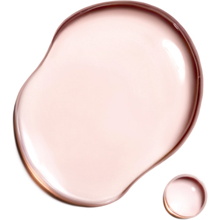 Clarins Super Restorative Treatment Essence 200 ml med en lett rosa og flytende tekstur som gir huden glød.