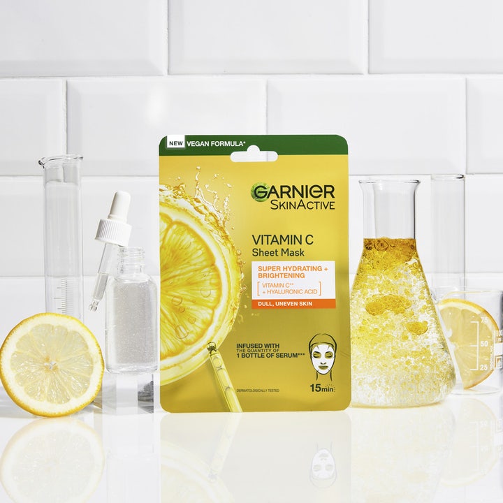 Garnier SkinActive Vitamin C Sheet Mask 28 g ansiktsmaske ved siden av sitroner og laboratorieglass