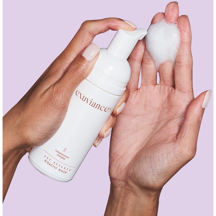 Exuviance Age Reverse BioActiv Wash 125 ml renseskum mot aldringstegn med hvit pumpeflaske og fyldig skum i en hånd
