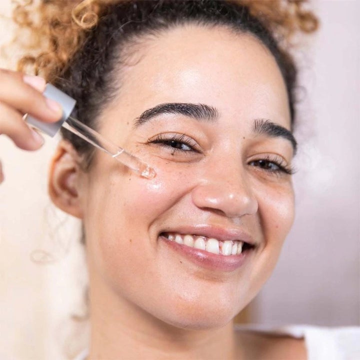 Dermalogica AGE Bright Clearing Serum Duo niacinamid serum kvinne påfører klart serum på kinnet med glasspipette