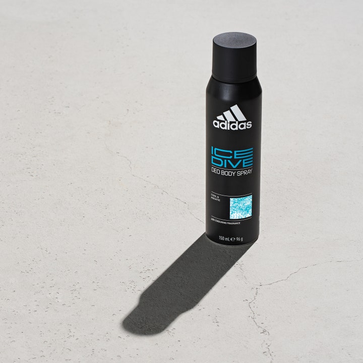 Adidas Ice Dive For Him 150 ml deodorant spray for herre i svart flaske med blå detaljer på lys betongoverflate.