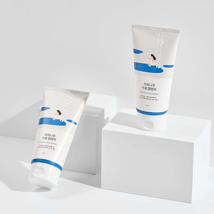Round Lab Birch Juice Moisturizing Cleanser 150 ml fuktighetsgivende ansiktsrens i hvite tuber på hvite podier.