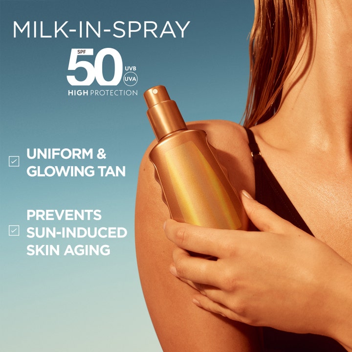 Garnier Ambre Solaire Ideal Bronze 150 ml solkrem SPF 50 gir jevn glød i gyllen sprayflaske holdt mot huden