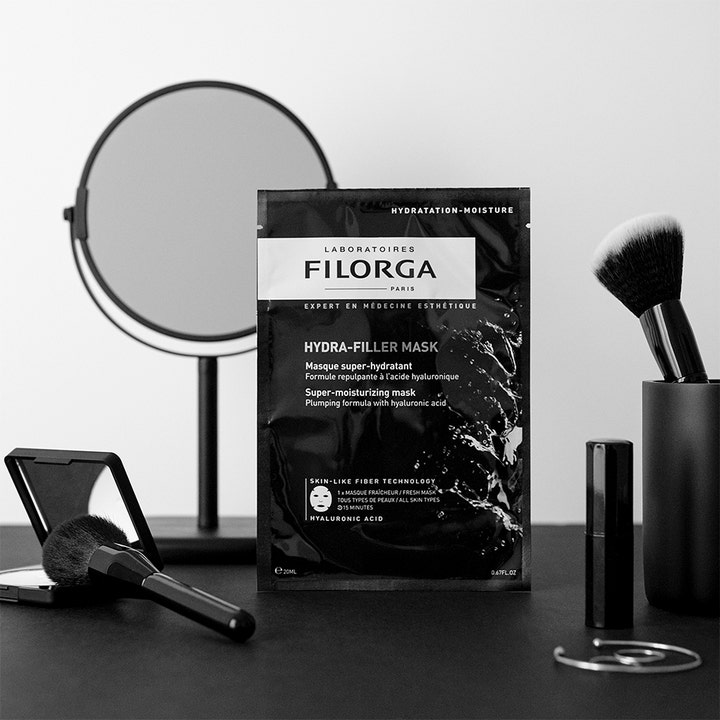 FILORGA Hydra-Filler Mask 23 g fuktighetsgivende sheetmaske i svart pose ved siden av sminkekoster og speil
