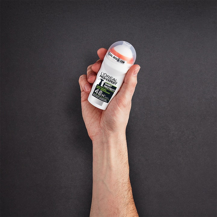 L'Oréal Paris Men Expert Shirt Protect 50 ml roll-on deodorant i en hånd mot mørk bakgrunn.