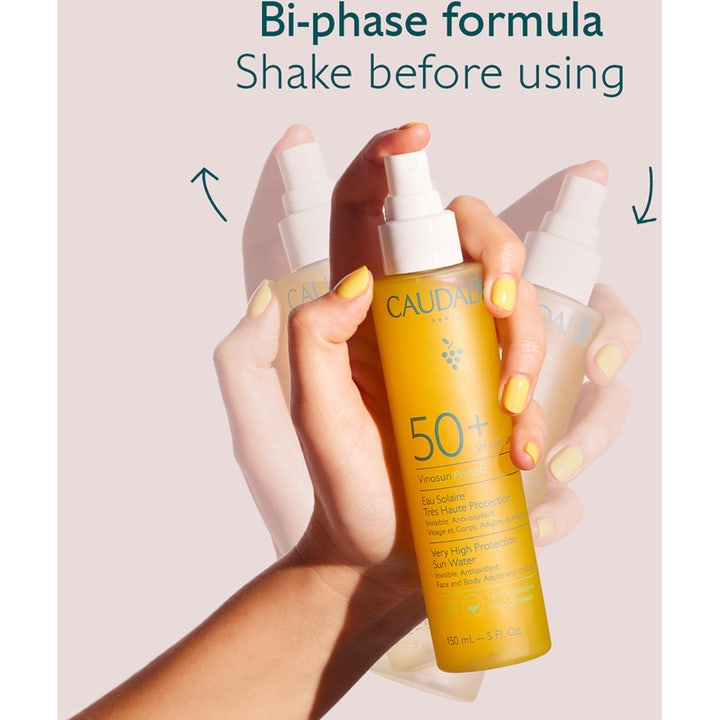 Caudalie Vinosun Very High Protection Water 150 ml solspray i en hånd som rister tofaseformelen