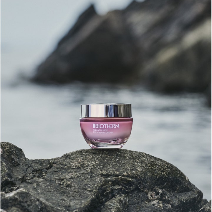 Biotherm Aquasource Cica Nutri 30 ml fuktighetsgivende dagkrem i rosa glasskrukke plassert på en stein ved sjøen