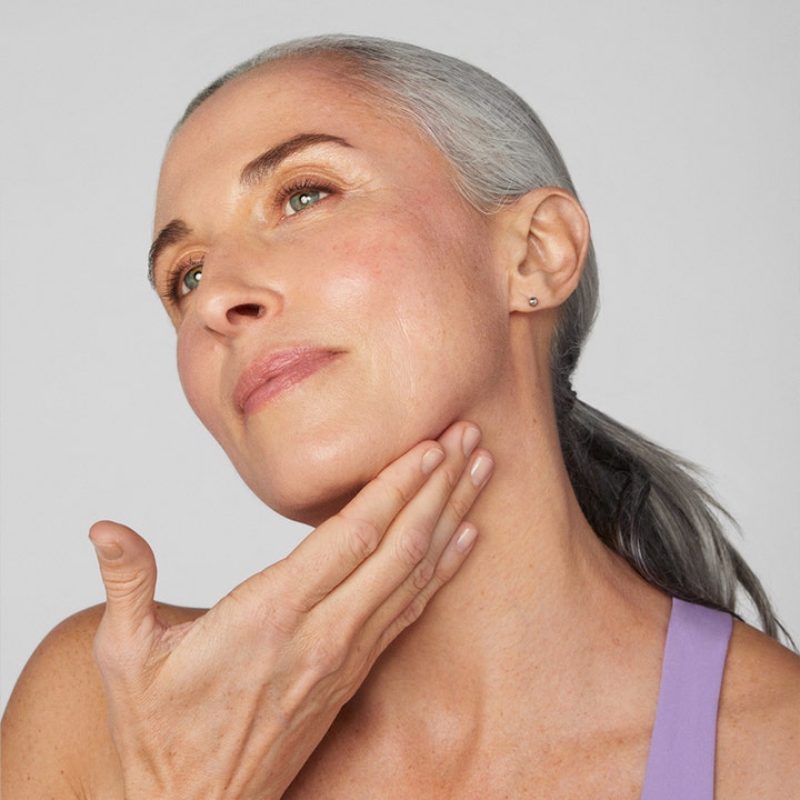 Clinique Smart Clinical Repair Lifting Face + Neck Cream 50 ml løftende ansiktskrem kvinne som påfører krem på hals og kjeve