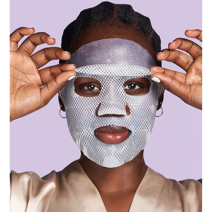 Exuviance Pick-Me-Up Plumping Mask 20 g sheetmaske som gir fukt til en kvinne som påfører masken over ansiktet.