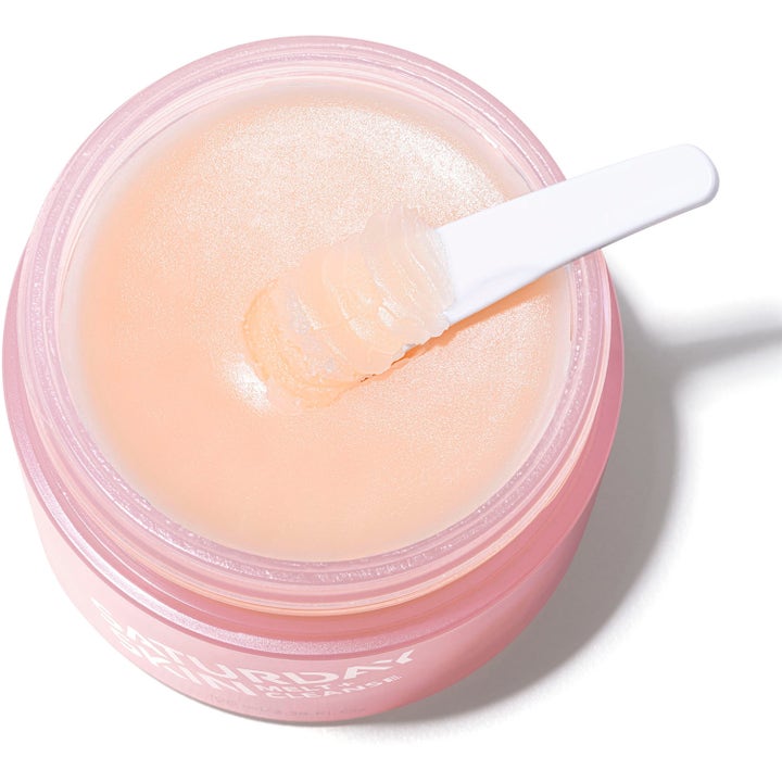 Saturday Skin Melt + Cleanse 100 ml ansiktsrens i rosa krukke med hvit spatel som løfter opp balm-tekstur