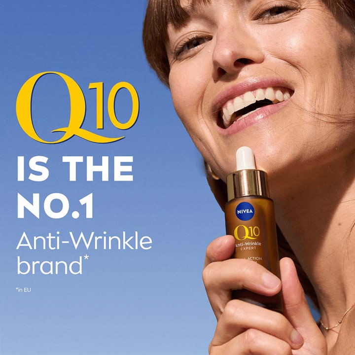 Nivea Q10 Anti-Wrinkle Expert Dual Action 30 ml serum mot rynker holdt av en smilende kvinne i sollys.