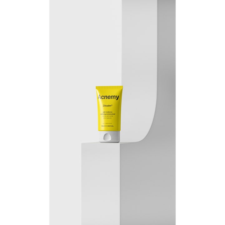 Niche Beauty Lab Acnemy Zitcalm 50 ml beroligende ansiktskrem mot rødhet i gul tube på hvit geometrisk hylle.