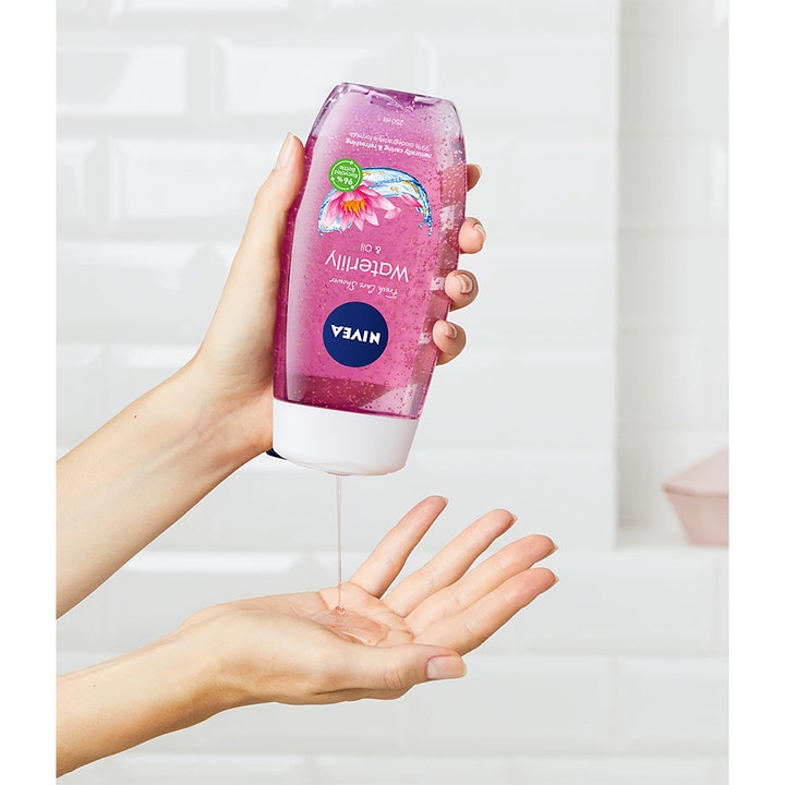 NIVEA Waterlily & Oil 250 ml pleiende dusjsåpe helles fra lilla flaske i en hånd og viser gelé med oljeperler
