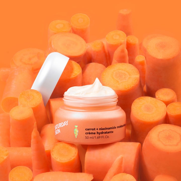 Saturday Skin Carrot + Niacinamide Moisturizing Cream 30 ml i krukke omgitt av ferske gulrøtter.