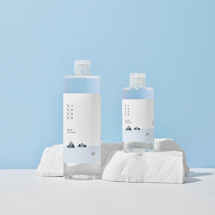 Round Lab 1025 Dokdo Toner 200 ml fuktighetsgivende ansiktsvann i klare flasker på hvite steiner mot blå bakgrunn