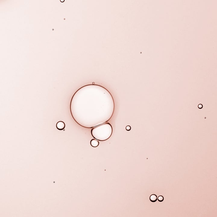 KORA Organics Turmeric Glow Drops 10 ml ansiktsserum med en lett rosa tekstur og klare bobler