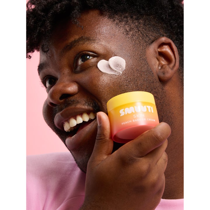 Smuuti Skin Peach Barrier Cream 50 ml styrkende ansiktskrem vist på en smilende person med hjerteformet krem på kinnet