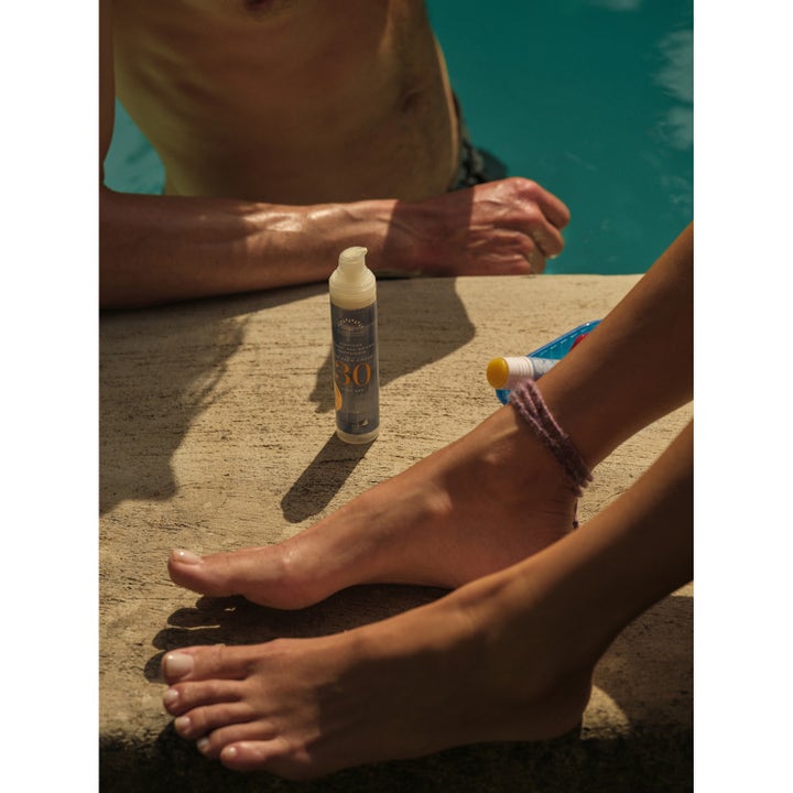 Rudolph Care Sun Face Cream SPF30 50 ml solkrem for ansiktet gir solbeskyttelse i pumpeflaske ved et basseng.