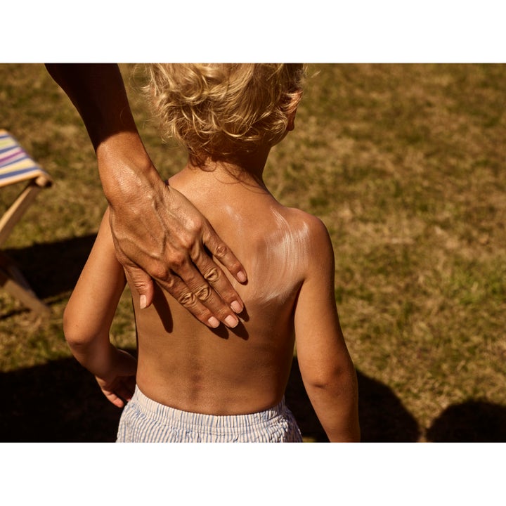 Rudolph Care Sun Lotion Kids SPF50 200 ml beskyttende solkrem som smøres på et barns rygg i solen