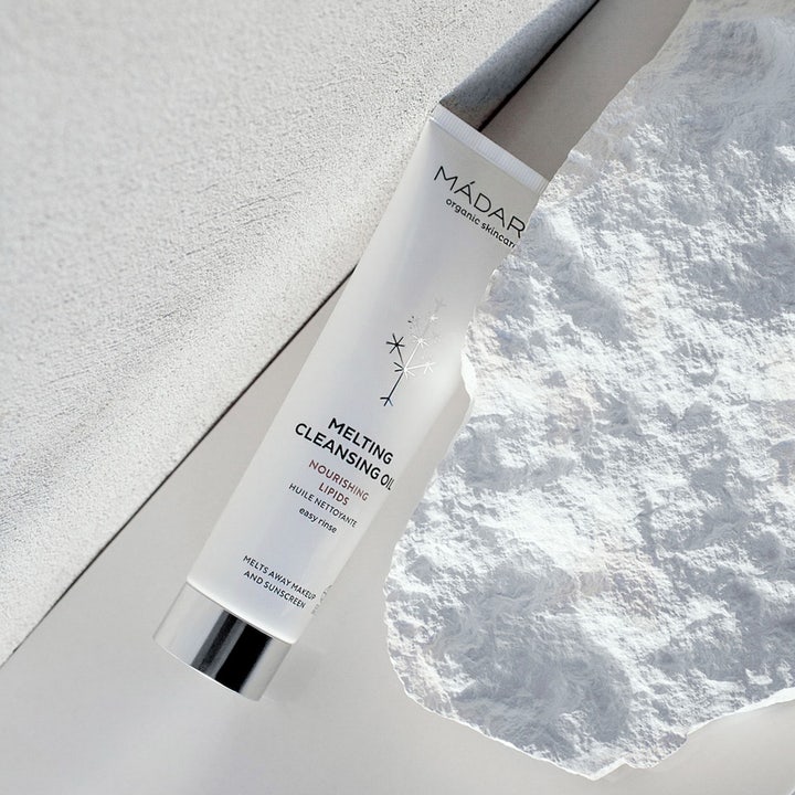 MÁDARA Melting Cleansing Oil 100 ml ansiktsrengjøring fjerner makeup i hvit tube med sølvkork på hvit tekstur.