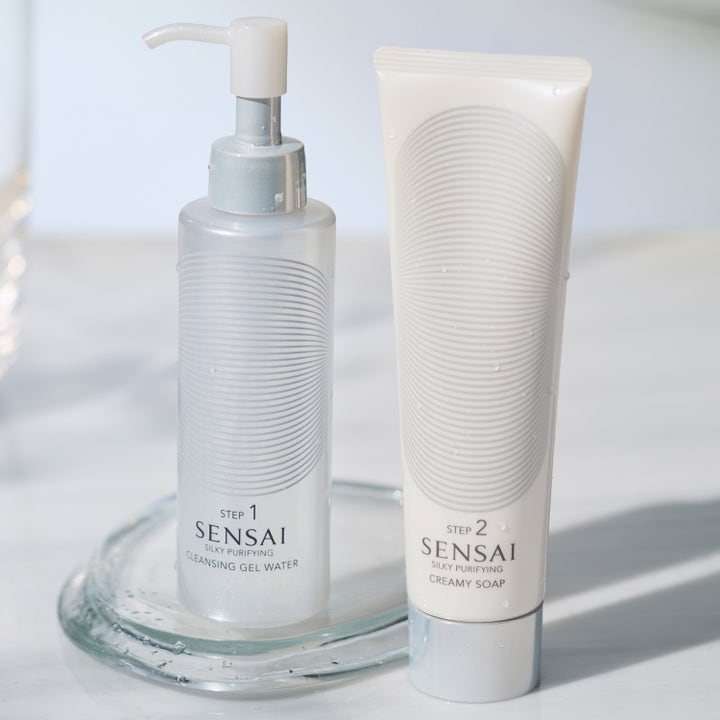 Sensai Silky Purifying Cleansing Gel Water 150 ml ansiktsrens i frostet pumpeflaske og hvit tube på et elegant glassfat