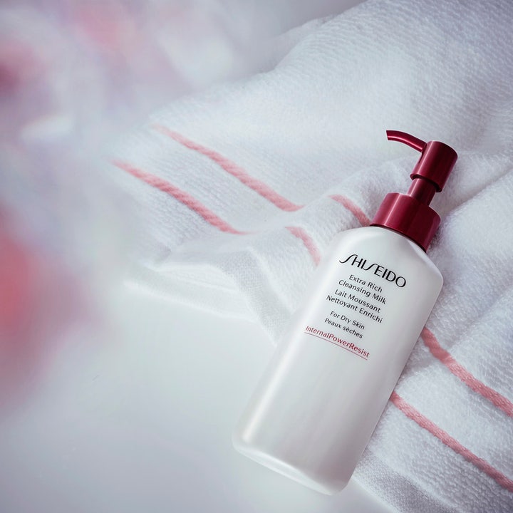 Shiseido Defend Extra Rich Cleansing Milk 125 ml ansiktsrens for tørr hud i hvit flaske med rød pumpe på et håndkle