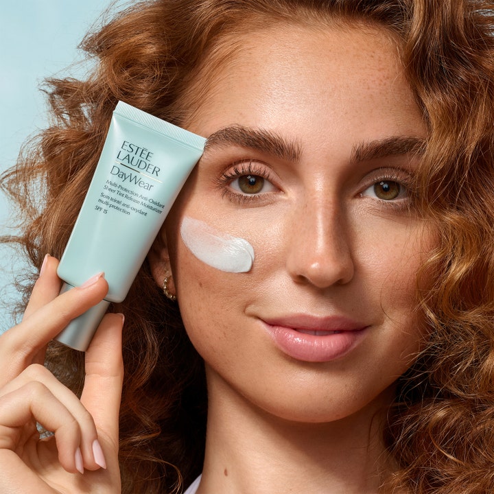 Estée Lauder DayWear Sheer Tint Moisturizer 30 ml fuktighetskrem på tube vist med hvit krem på kinnet til kvinne