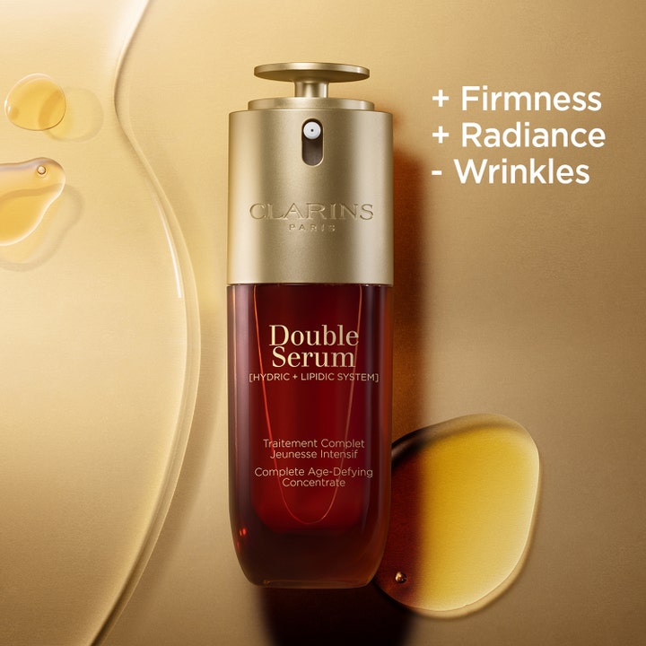 Clarins Double Serum 50 ml gir fasthet og glød mot rynker i ravfarget pumpeflaske omgitt av gylne serumdråper.