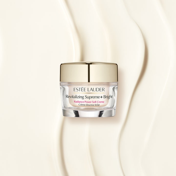 Estée Lauder Revitalizing Supreme+ Bright 50 ml glødgivende ansiktskrem i glasskrukke mot bølger av kremet tekstur