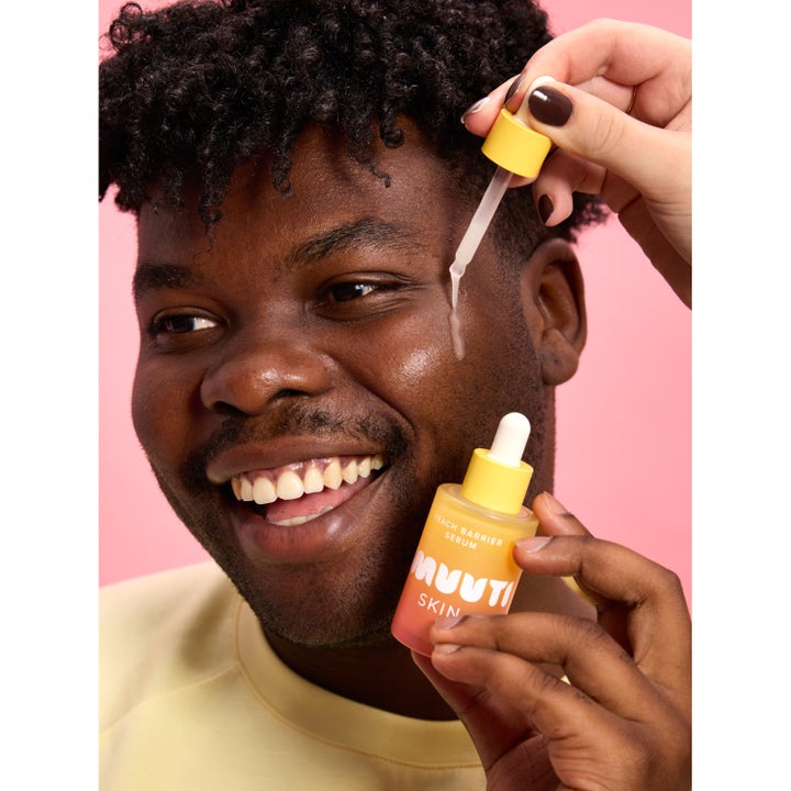 Smuuti Skin Peach Barrier Serum 30 ml fuktighetsgivende serum påføres med pipette på huden til en smilende mann.