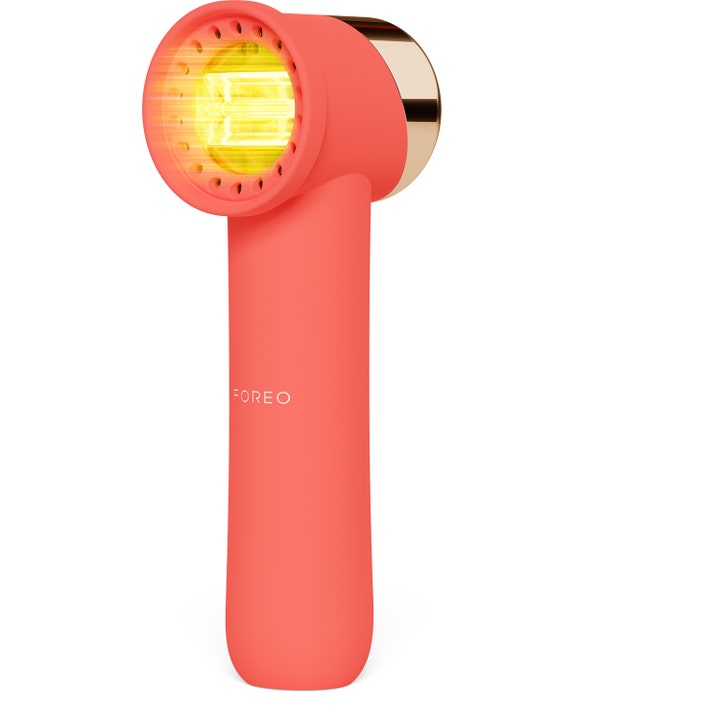Foreo FAQ 102 hudpleieapparat for hudforyngelse i korallrødt design med gult LED-lys og detaljer i gull
