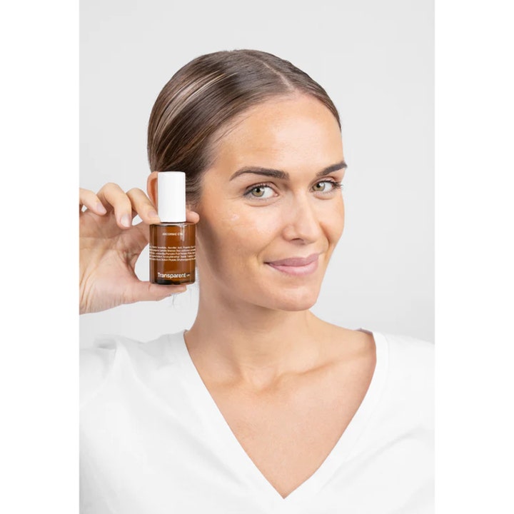Niche Beauty Lab Transparent Lab Ascorbic C15 Serum 30 ml glødgivende vitamin C-serum i brun glassflaske vist av kvinne