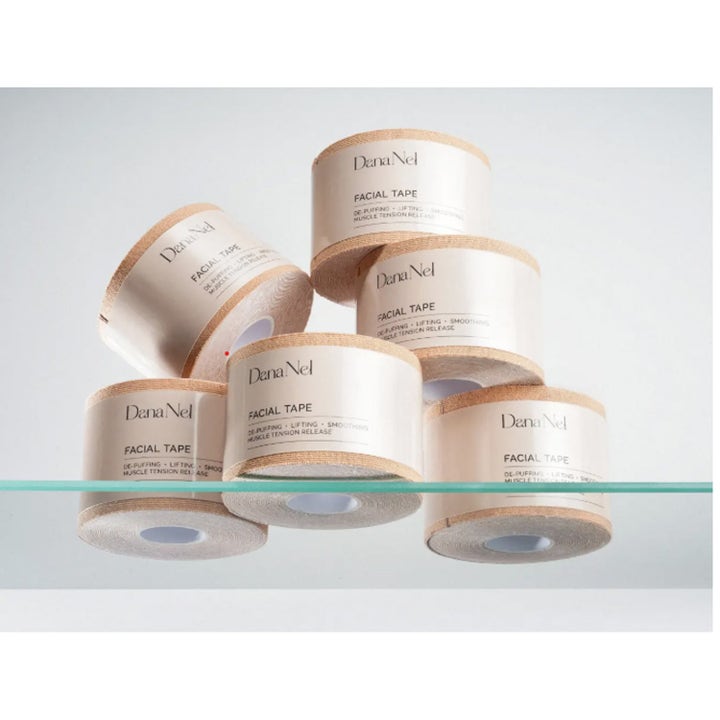 Dana Nel Facial Beauty Tape 1 stk utglattende ansiktstape beige ruller med kinesiologiteip stablet på glass