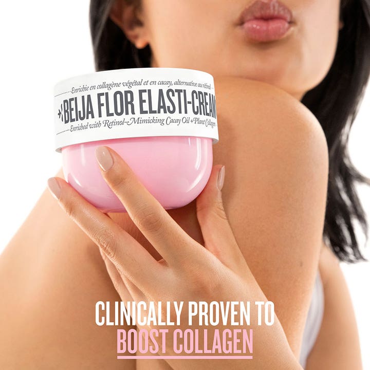 Sol de Janeiro Beija Flor Elasti Cream 240 ml body lotion som øker kollagen holdt mot bar hud i en rosa krukke.