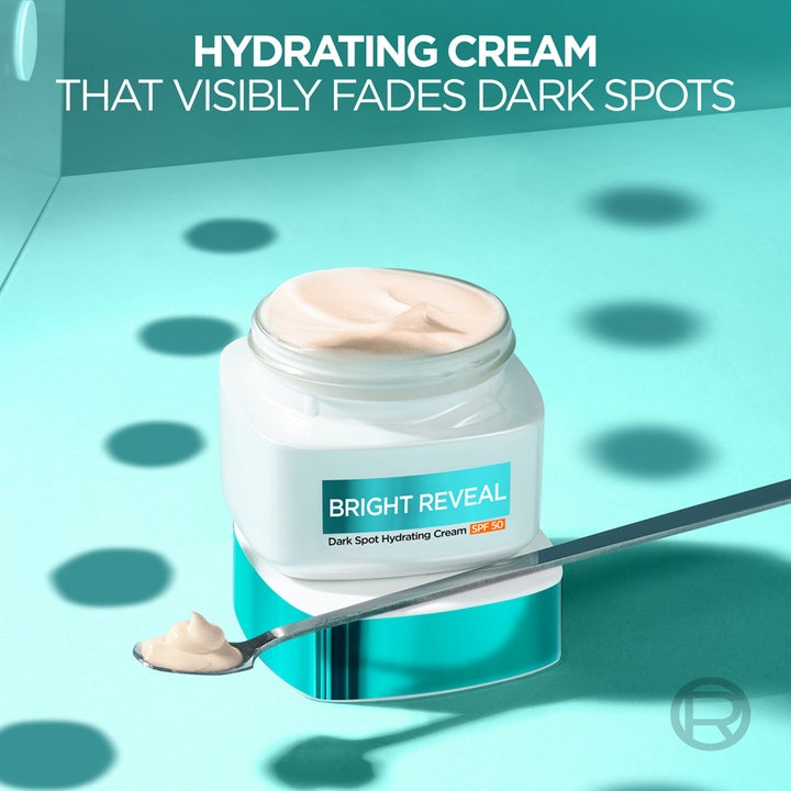 L'Oréal Paris Bright Reveal 50 ml dagkrem mot mørke flekker med SPF 50 i åpen krukke og på en liten skje.