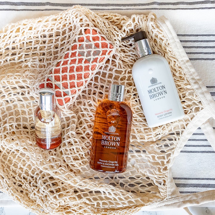 Molton Brown Heavenly Gingerlily Bath & Shower Gel 300 ml dusjsåpe i en beige nettingveske med matchende produkter.