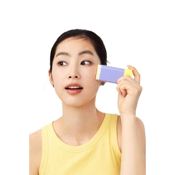 By Wishtrend Pore Smoothing Bakuchiol Sun Stick 18 g solkrem kvinne som påfører lilla og gul solstift på kinnet