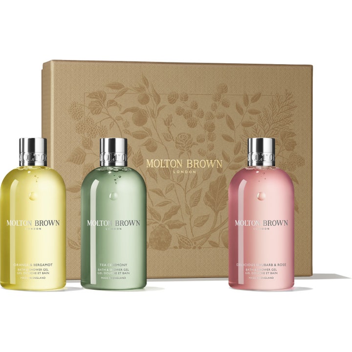 Molton Brown Bath & Shower Gel gaveesett gir en luksuriøs vask med tre fargerike flasker foran en mønstret gulleske
