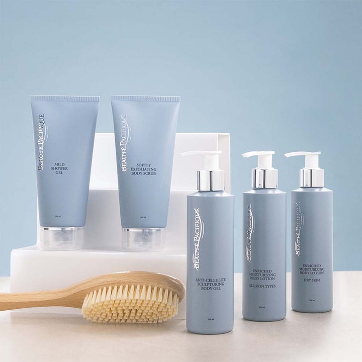 Beauté Pacifique kroppspleie 200 ml fuktighetsgivende produkter i lyseblå beholdere stående med en badebørste i tre
