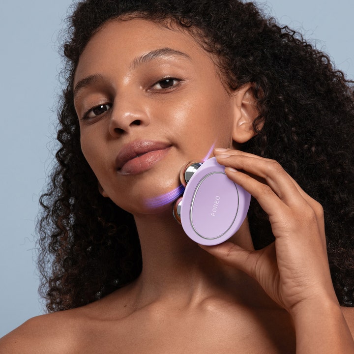 FOREO BEAR 2 Lavender 1 stk mikrostrømsenhet for ansiktsløft vist på kvinne som bruker enheten langs kjeven
